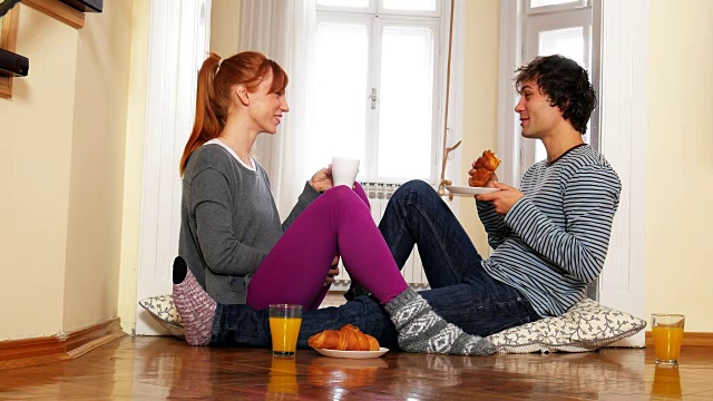 年轻夫妇在家里吃零食，享受他们的爱情和婚姻视频素材