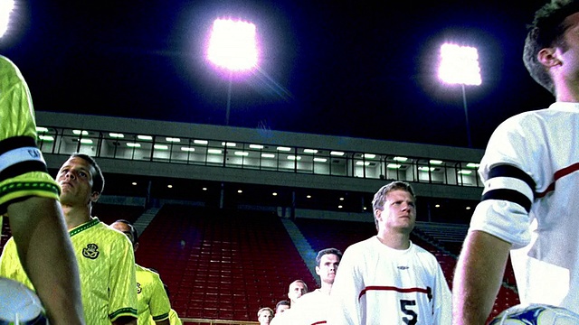 低角度跟踪拍摄的球员为2支足球队走到球场在晚上空体育场视频素材