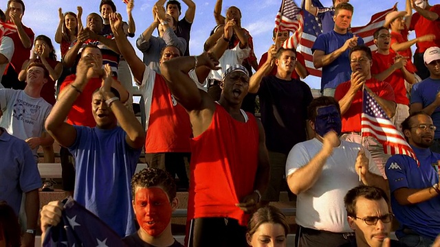 宽镜头吊车拍摄比赛期间站在露天看台上鼓掌的球迷，他们手持美国国旗视频下载