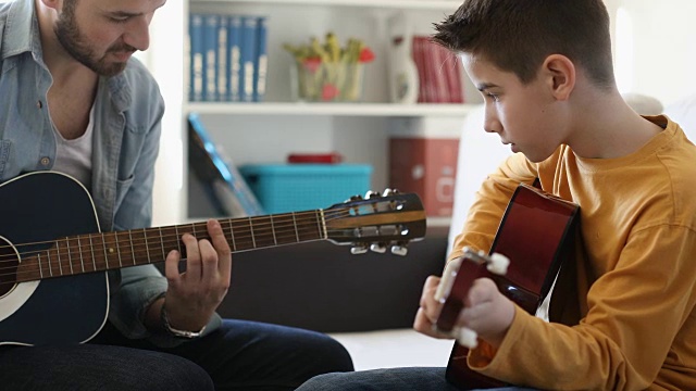 男孩在家里学弹吉他视频素材