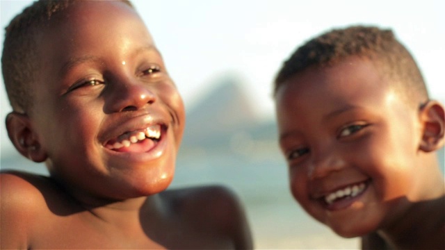 两个巴西男孩对着镜头微笑，在博塔弗戈海滩上歇斯底里地大笑视频素材