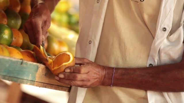 熟练的手在巴西市场用刀切橘子视频素材