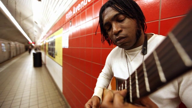 地铁经过车站时，一位街头音乐家在站台上弹奏着原声吉他视频素材