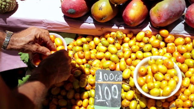巴西集市上，老农用双手摆放着caj水果视频素材