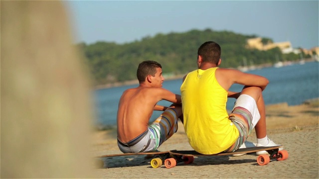 一名巴西少年滑着滑板走到朋友面前，和朋友握手，然后坐在滑板上视频素材