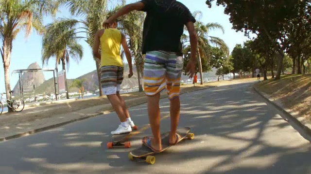 巴西朋友们在海边的街道上玩滑板，在远处玩甜面包视频素材