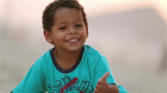 在科帕卡巴纳海滩，可爱的巴西男孩对着镜头竖起大拇指微笑视频素材