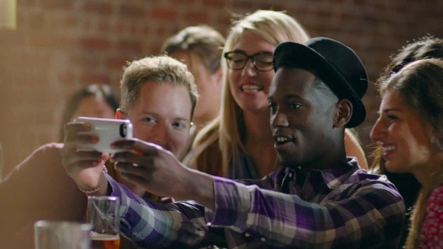一群朋友在拥挤的酒吧用智能手机自拍视频素材