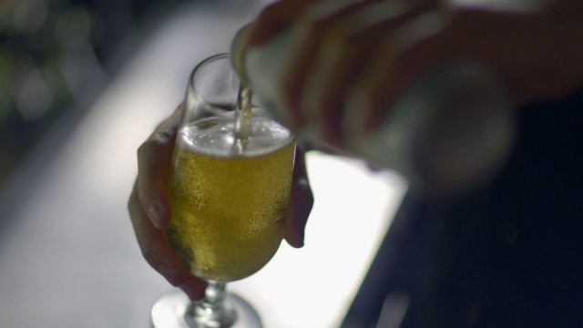 酒保把一罐啤酒倒进玻璃杯里视频下载