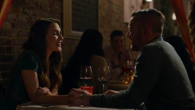 在浪漫的餐厅里，年轻夫妇隔着桌子手牵手聊天视频下载