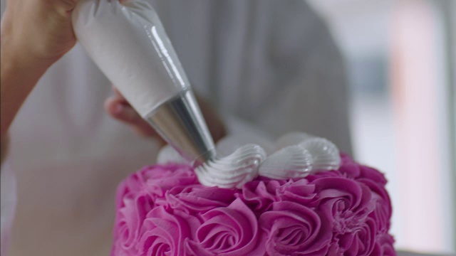 糕点师用白色糖衣装饰粉色蛋糕视频素材