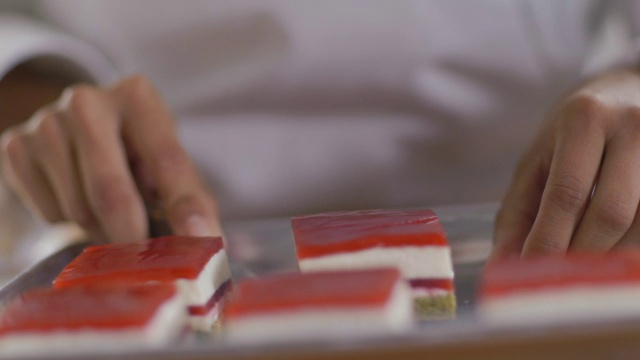 糕点师的双手将蛋糕从托盘中取出并放在甜点盘上视频素材