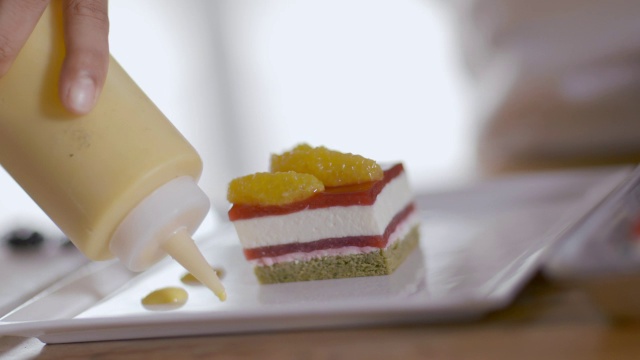糕点师傅用榨汁瓶中的黄酱装饰甜点视频下载