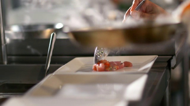 在餐厅厨房里，美食厨师用勺子把热气腾腾的扇贝盛在餐盘里视频下载