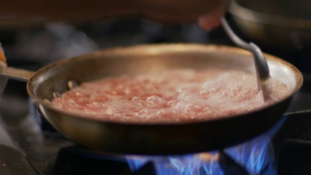 厨师在餐厅厨房里用平底锅在火辣辣的炉子上搅拌煮熟的扇贝视频素材