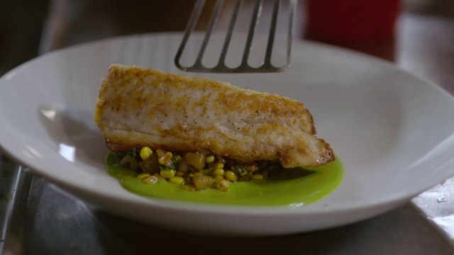 在餐厅厨房里，厨师把鱼片放在煮玉米上，放在美味的餐盘上视频素材