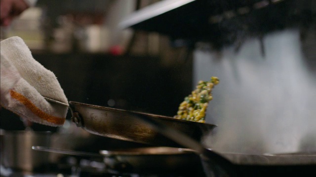 餐厅厨师用慢动作将玉米放入铁煎锅中视频素材