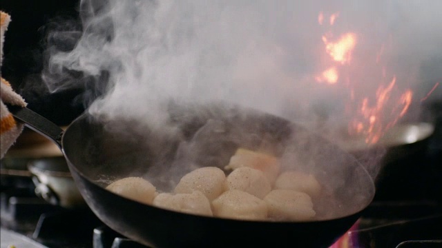 餐厅主厨用慢动作将煎锅里的扇贝摇到燃烧的炉子上视频下载