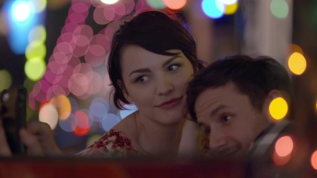 一对年轻夫妇在五颜六色的奥斯汀酒吧里用智能手机自拍视频素材