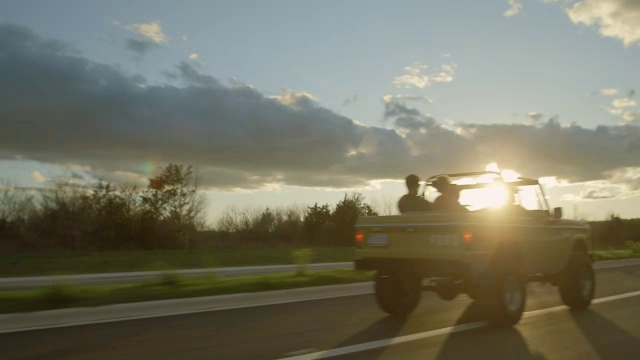 朋友们开着经典的福特野马在夕阳中飞驰视频素材