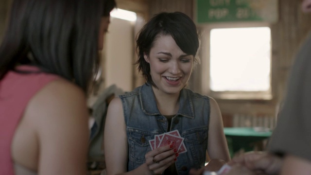 年轻女子在和朋友们一起玩扑克牌时大笑视频下载