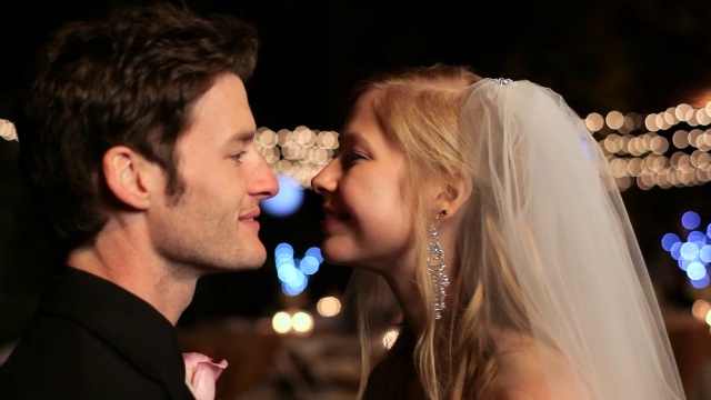 手持式近距离拍摄年轻幸福的新娘和新郎亲吻仪式后在晚上户外视频素材