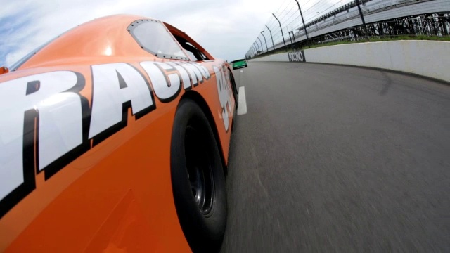 橙色的汽车司机跟在绿色的赛车后面一辆橙色的汽车在跑道上比赛。视频下载