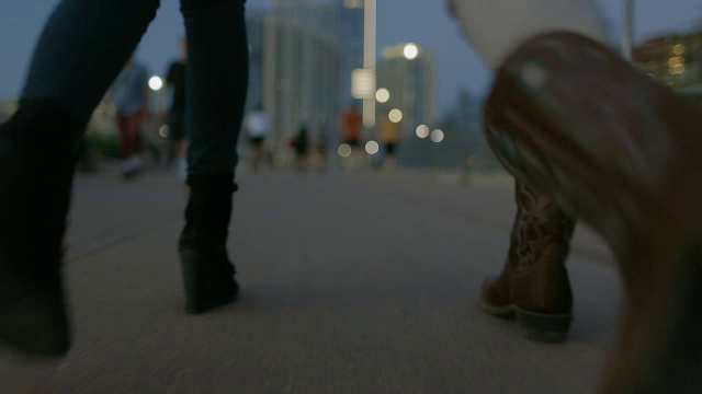 低跟踪拍摄的朋友的脚在晚上走过人行桥视频素材