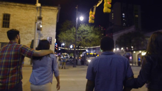 年轻的情侣们晚上一起穿过德克萨斯州奥斯汀市中心的街道视频素材