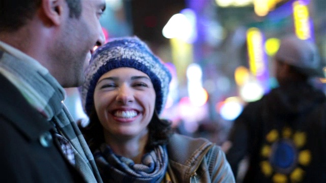 在时代广场的灯光下，年轻女子笑着亲吻男友的脸颊视频素材