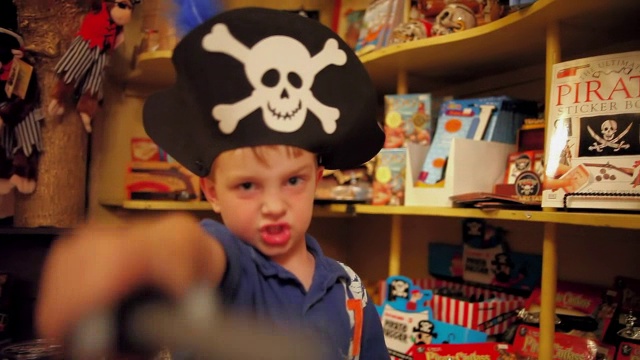 戴着海盗帽的小男孩在玩具店拿着玩具匕首视频下载