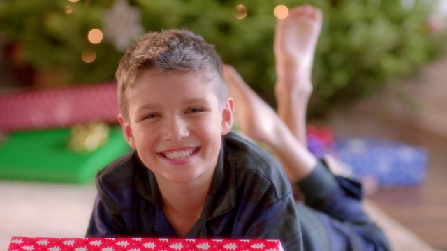 小男孩在圣诞树前对着相机微笑视频素材