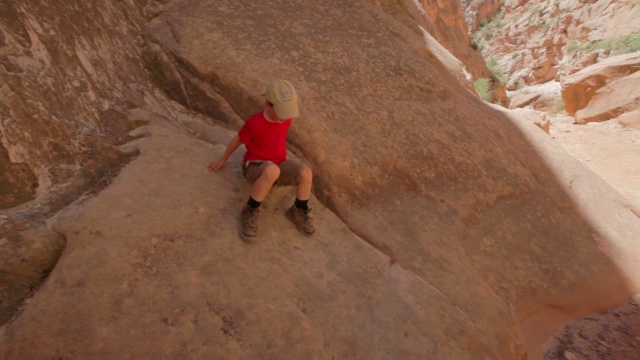 小男孩滑下陡峭的峡谷壁，骄傲地跳到尘土飞扬的小路上视频素材