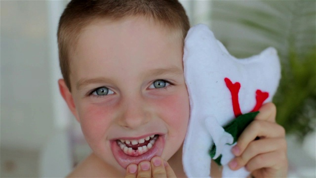 一个小男孩高兴地展示他缺了的门牙，拿着他的牙仙枕头视频下载