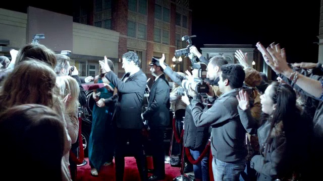在颁奖典礼的红地毯上，一对好莱坞夫妇从豪华轿车中爬出来，向粉丝和狗仔队打招呼视频下载