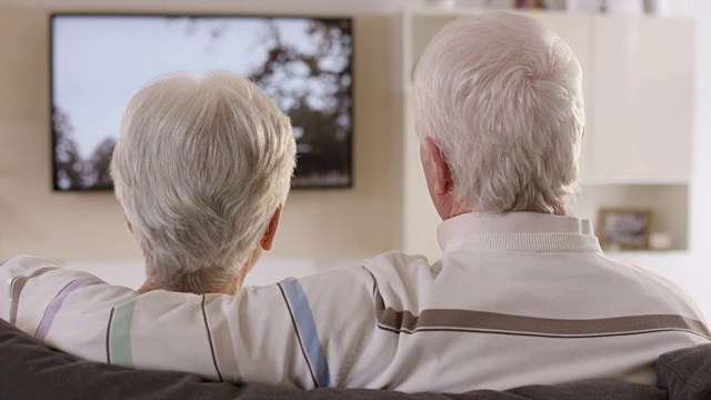 老男人一边和妻子看电视一边聊天视频素材