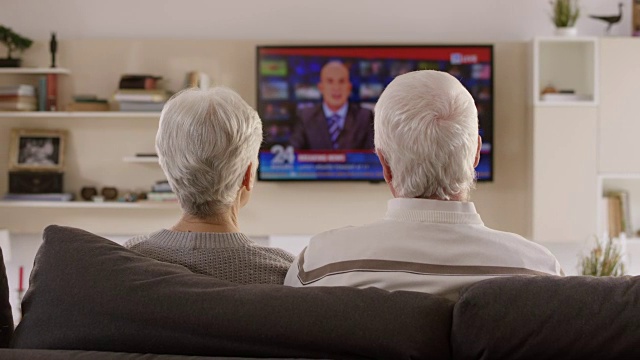一对老年夫妇正在讨论他们正在看的电视新闻视频素材