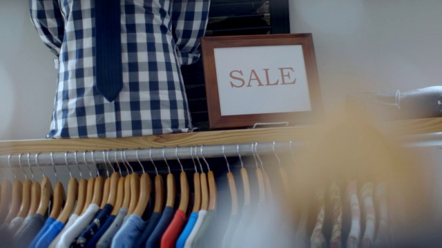 小企业员工将销售标志放在衣架上方的架子上视频素材