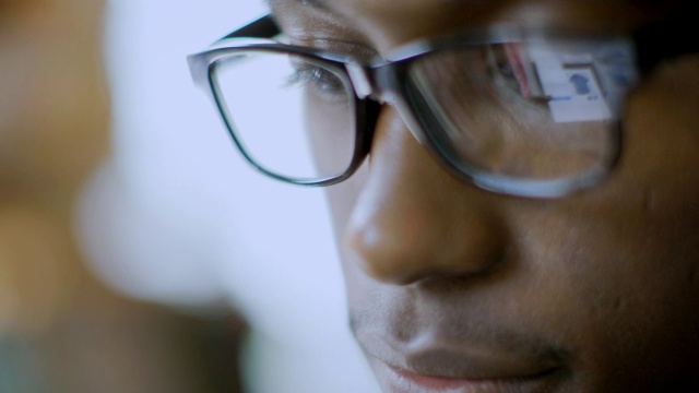 这位年轻人在网上服装店购物时，他的眼镜映出了他的平板电脑视频下载