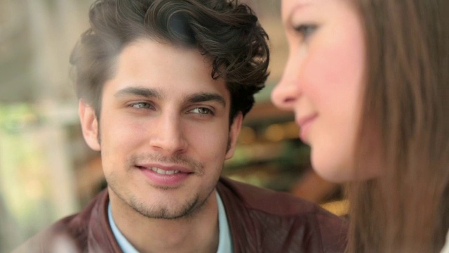一对年轻夫妇坐在咖啡店里互相凝视着对方的眼睛。视频素材