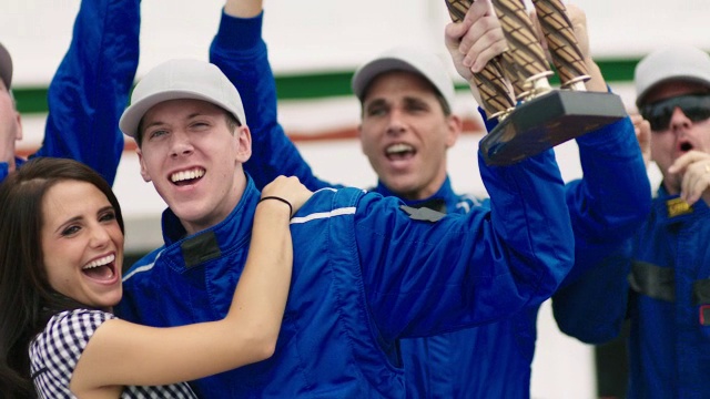 赛车手举起奖杯，蓝色车队庆祝赛车胜利视频素材