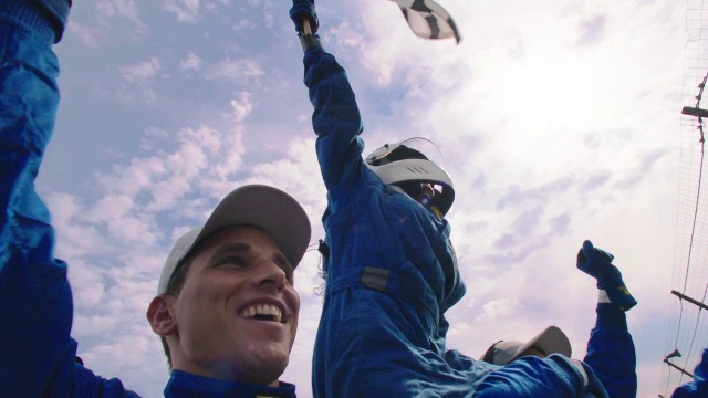 女子在赛车头盔波浪格子旗;蓝色赛车队举起女子，庆祝赛车胜利视频素材