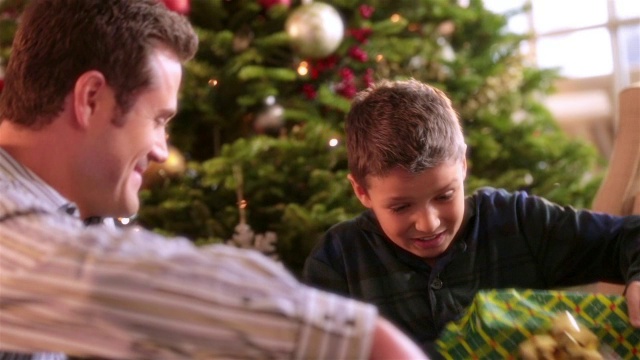 小男孩在圣诞树前疯狂地撕掉包装纸视频素材