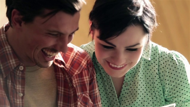 年轻夫妇与平板微笑和大笑汽车旅馆的床上视频素材