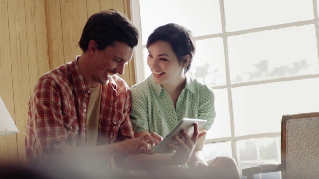 时髦的年轻夫妇在平板电脑上滚动和大笑视频素材
