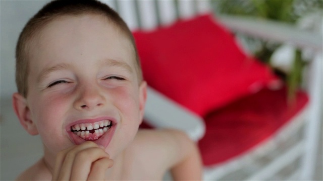 一个小男孩微笑着拉下他的下唇，露出他失去的门牙视频素材