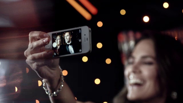 在颁奖典礼上，当狗仔队的相机在外面闪光时，明星夫妇用智能手机摆姿势自拍视频素材