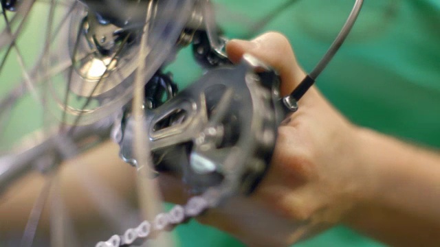 熟练的自行车机修工在修理厂用他的手在滑轮上旋转自行车车轮视频下载