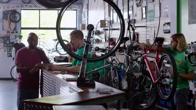 车间工作人员将价格标签挂在新自行车上，并通过平板电脑管理库存视频素材