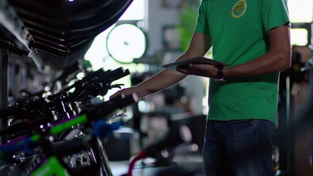 车间工人在平板电脑上输入数据，并将价格标签挂在新自行车上视频素材